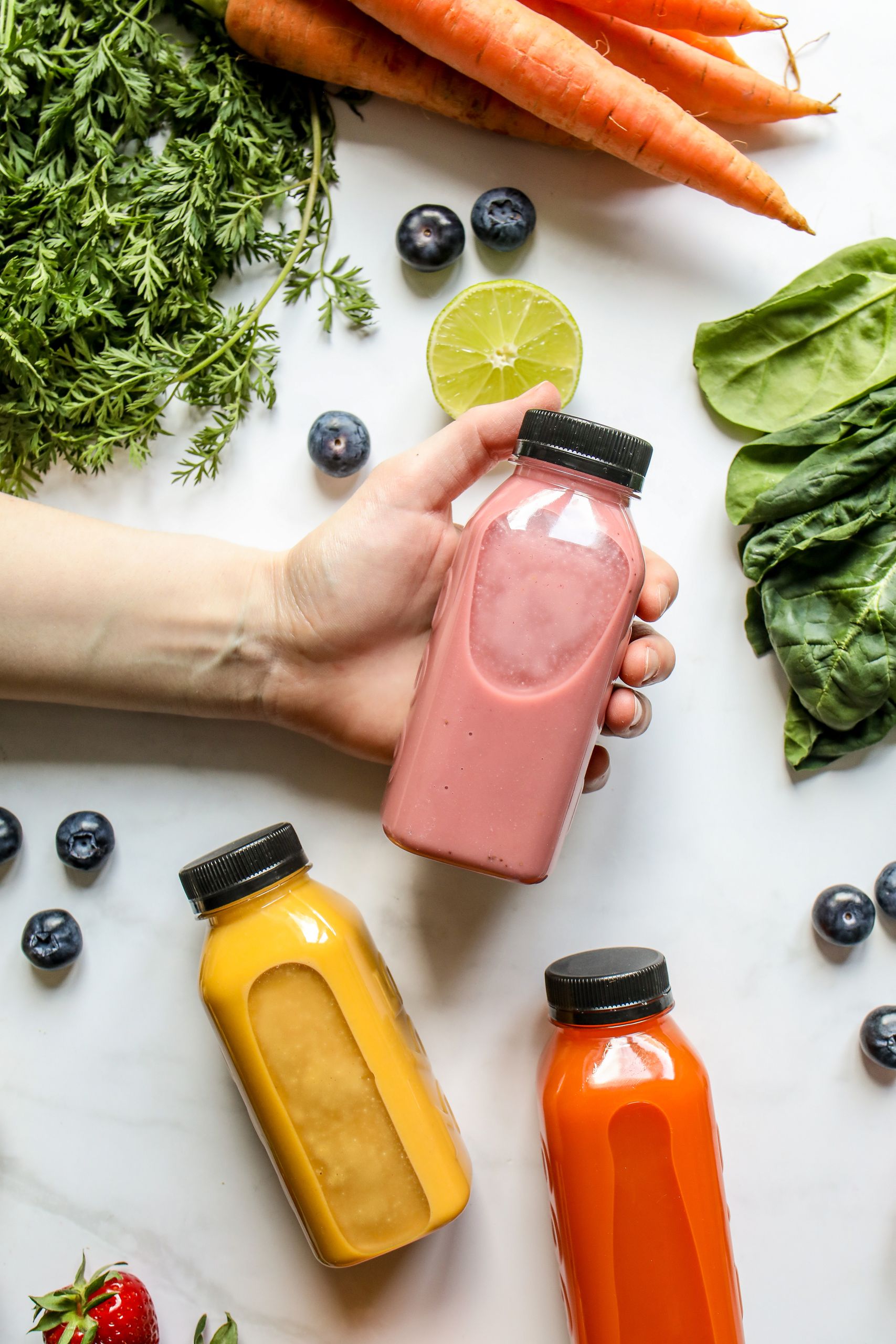 Colorful juices in bottles surrounded by fresh fruits and vegetables, promoting healthy living.